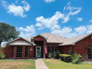 Large home with long driveway, lush lawn, and newly installed roof.